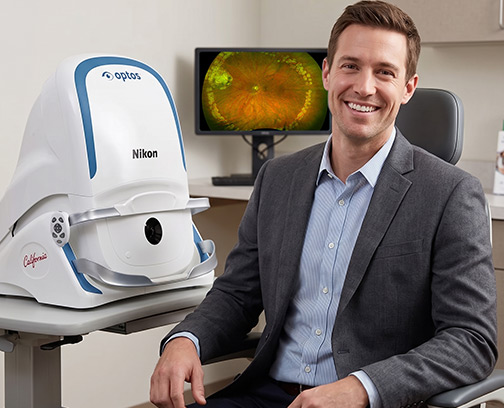 Smiling man sitting with Optos machine
